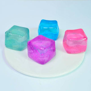 Four colorful ice cube-shaped objects on a white plate with a light blue background