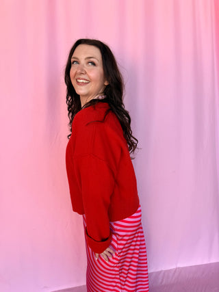 girl wearing a red sweater on a pink background