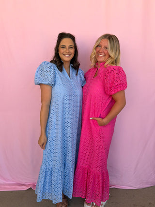 Two women wearing blue and pink dresses against a pink background