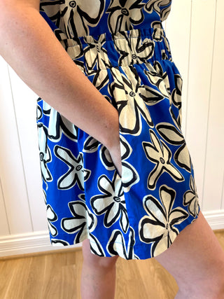 Person wearing a blue dress with white and black floral patterns.