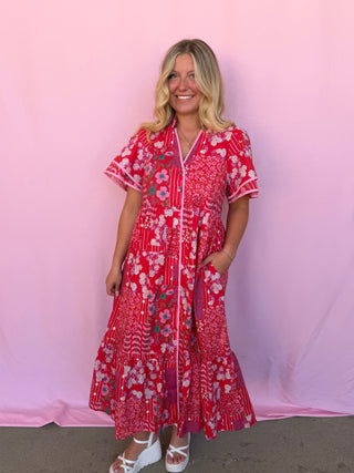 Woman wearing a red floral dress against a pink background