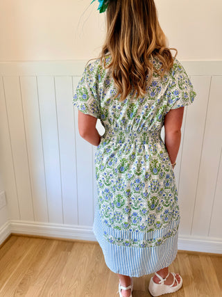 Woman wearing a floral dress with a white paneled wall in the background