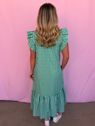 Person wearing a green checkered dress against a pink background
