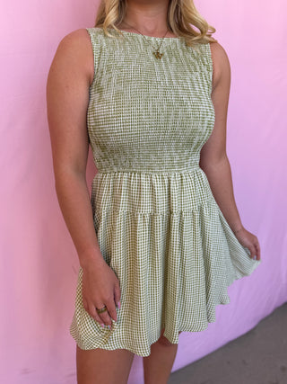 Woman wearing a green checkered dress against a pink background