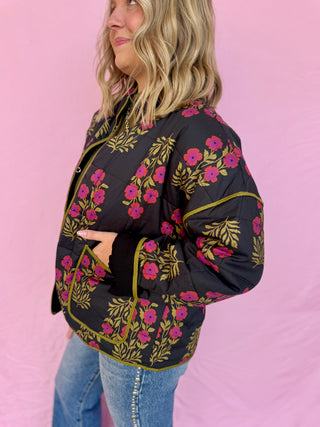 Woman wearing a black floral jacket against a pink background