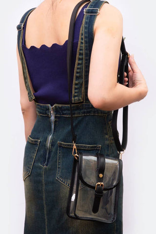 Person wearing denim overalls with a black leather bag on a white background