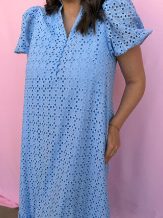 Woman wearing a blue patterned dress against a pink background