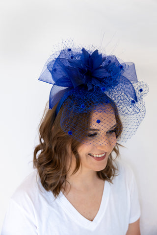 Woman wearing a blue fascinator with a veil on a white background