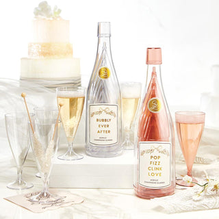 Two bottles of champagne labeled 'Bubbly Ever After' and 'Pop Fizz Clink Love' with glasses on a decorative tablecloth.