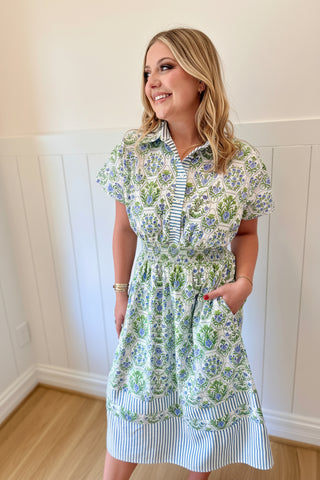 Woman wearing a floral dress and large blue headpiece indoors.