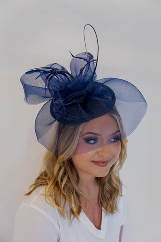 Woman wearing a navy blue fascinator on a white background