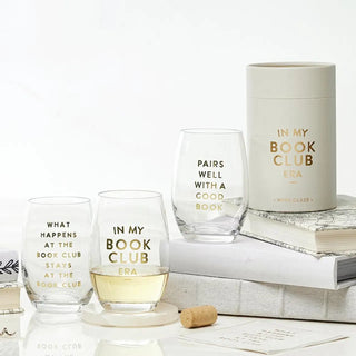 Set of wine glasses with 'In My Book Club' text on a white surface with books and a cork.