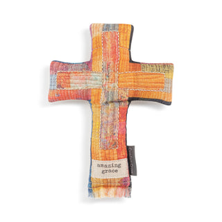 Multicolored cross-shaped pillow with 'amazing grace' tag on a white background