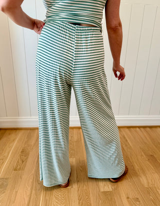 Person wearing a green and white striped outfit on a wooden floor with a white wall background