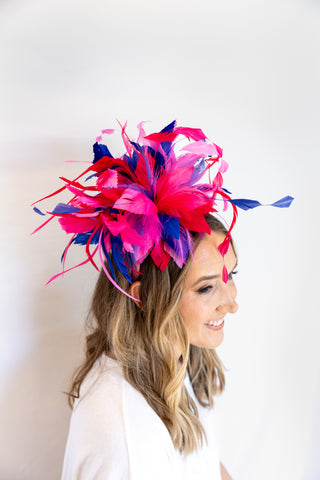 Woman wearing a colorful feathered headpiece against a white background