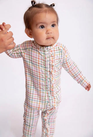 Baby wearing a colorful checkered outfit on a white background
