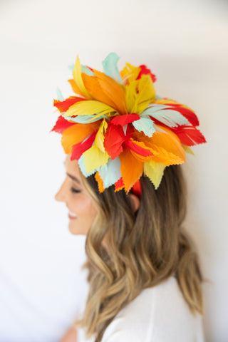 Woman wearing a colorful flower headpiece against a white background