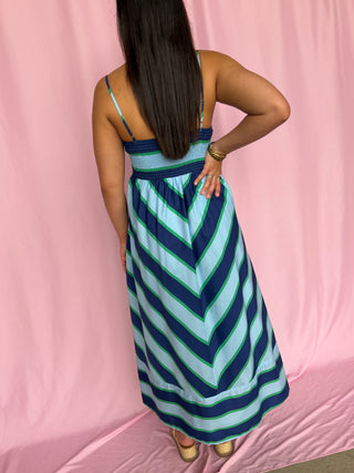 Woman wearing a blue and green striped dress against a pink background
