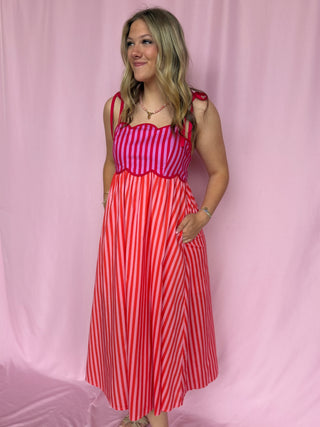 Woman wearing a red and white striped dress against a pink background
