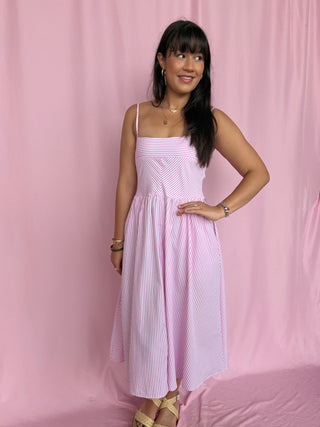 Woman wearing a pink and white striped dress against a pink background