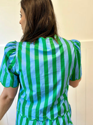 Person wearing a green and blue striped dress with puffed sleeves against a plain background