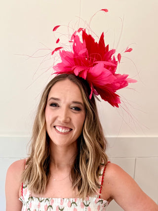 Woman wearing a large pink feathered headpiece against a white background