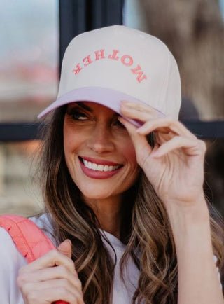Woman wearing a pink cap with 'MOTHER' text, holding a red bag.