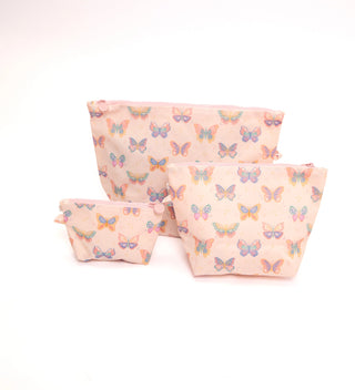 Three soft fabric pouches in different sizes with a pastel pink background and a repeating colorful butterfly print, arranged on a white studio background.