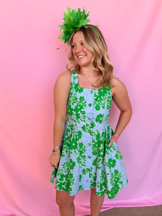 Woman wearing a green and blue floral dress with a pink background