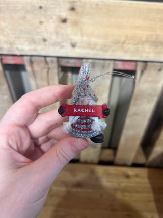 Small crocheted airplane keychain with a red label held by a hand against a wooden background