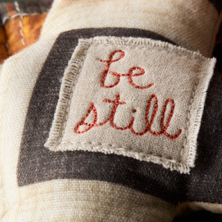 Textile patch with 'be still' embroidery on a fabric background