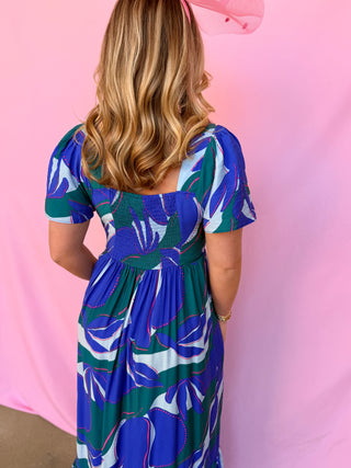 Woman wearing a blue floral dress against a pink background