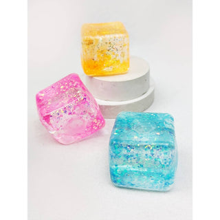 Three colorful resin cubes on a white pedestal stand against a white background