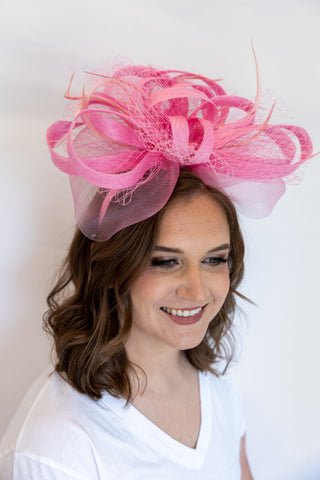 Woman wearing a large pink decorative headpiece against a white background