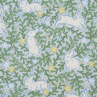 Fabric pattern with white bunnies and green leaves on a blue background