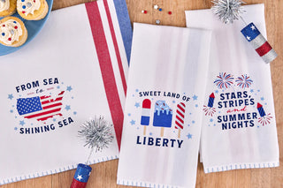 Three decorative towels with patriotic designs on a wooden surface.