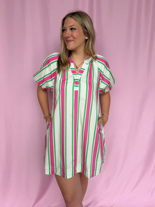 Woman wearing a striped dress against a pink background