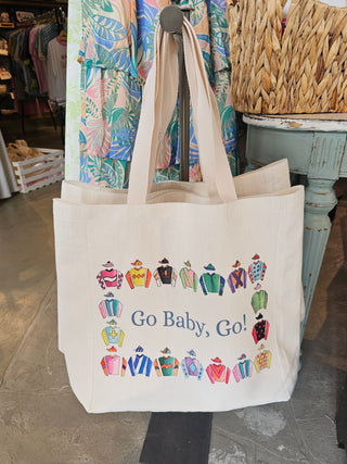 Beige tote bag with colorful horse racing jockeys and text 'Go Baby, Go!' in a store setting.