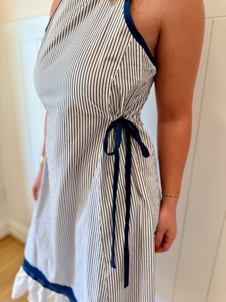 Woman wearing a striped dress with blue accents in a minimal indoor setting