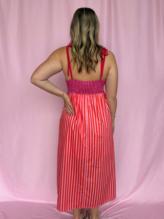 Woman wearing a red and white striped dress against a pink background