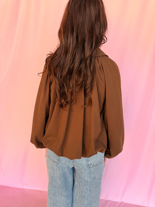 girl wearing a brown shirt on a pink background 