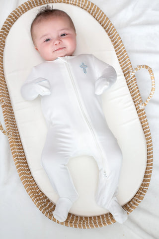 Baby in a white onesie lying in a textured oval basket