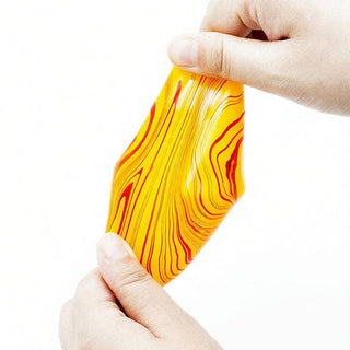 A person's hands stretching a translucent, wavy yellow and orange object with red marbled streaks against a plain white background.
