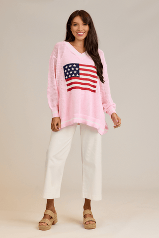 Woman wearing a pink sweater with an American flag design on a beige background