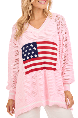 Pink sweater with American flag design worn by a model on a white background