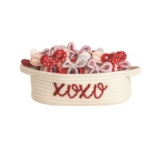 Basket filled with decorative bows and embroidered with 'XOXO' on a white background