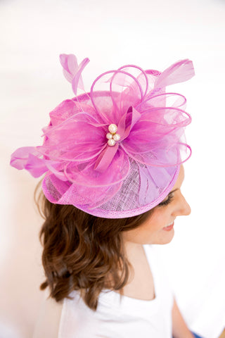 Woman wearing a pink decorative headpiece with pearls on a white background