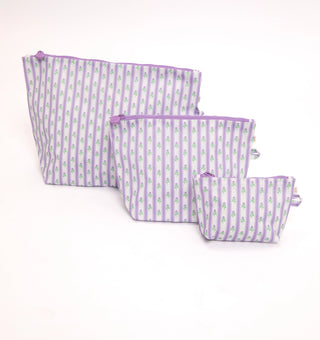 Three fabric zip pouches in a nested set, featuring a light purple and white vertical stripe pattern with small green floral motifs, set against a plain white background.