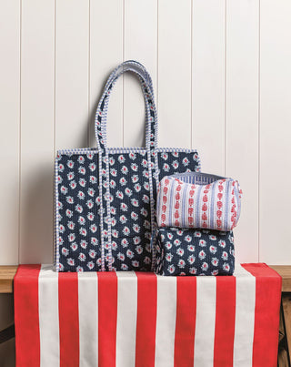 Set of floral-patterned bags on a table with a red and white striped cloth against a wooden panel background
