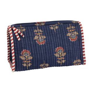 A quilted navy blue cosmetic pouch with a floral block-print pattern in red, gold, and white, featuring red and white striped fabric handles on the sides.